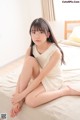 A woman sitting on a bed with her legs crossed.