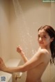 A naked woman taking a shower in a bathroom.