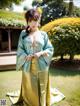 A woman in a green and yellow kimono posing for a picture.