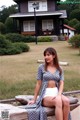 A woman sitting on a log in front of a house.