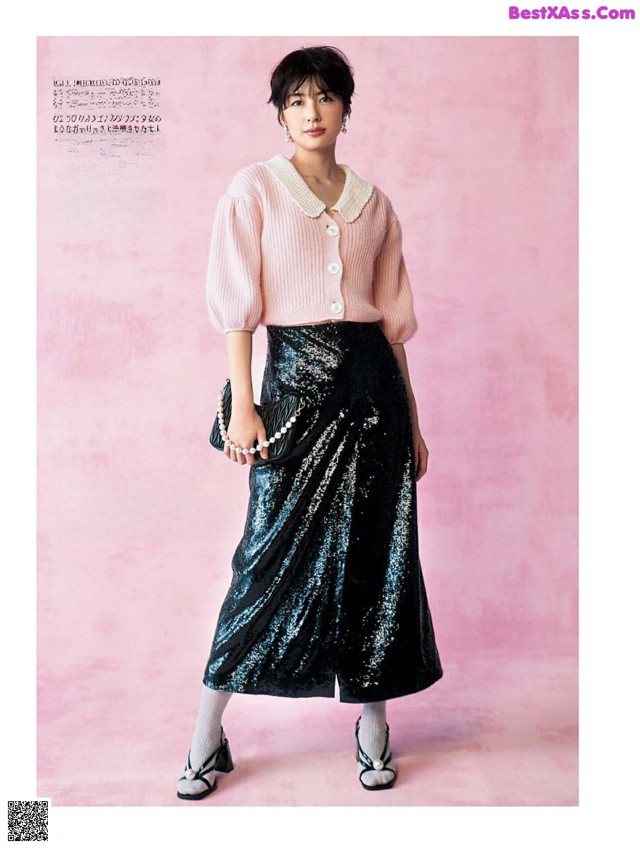 A woman in a pink sweater and black skirt posing for a magazine.