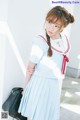 A woman in a blue and white uniform leaning against a wall.