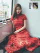 A woman in a red dress sitting on a window sill.