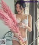 A woman in a white lingerie holding a pink feather fan.