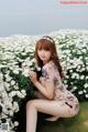 A woman sitting in a field of white flowers.