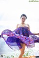 A woman in a purple dress standing on a dock.