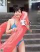 A woman in a blue bikini holding a cup of ice cream.