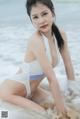 A woman in a white bikini sitting in the water.