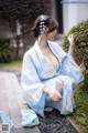 A woman in a blue kimono sitting on the ground.