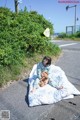 A woman sitting on a blanket with a teddy bear.