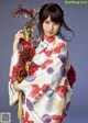 A woman in a kimono holding a bunch of flowers.