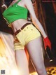 A woman in a green top and yellow shorts holding a gun.