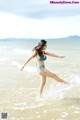 A woman in a blue bikini standing in the ocean.