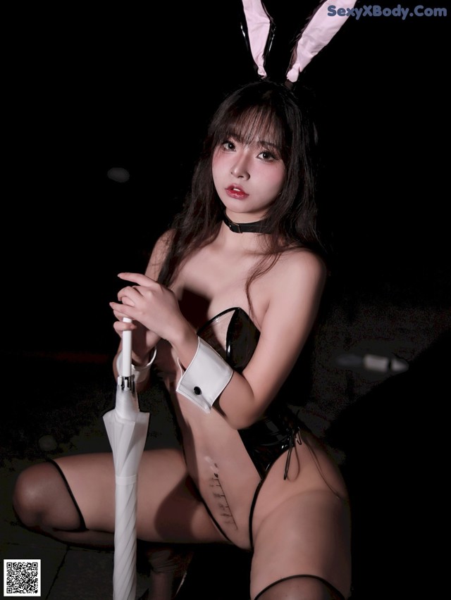 A woman in a bunny costume holding an umbrella.