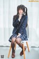 A woman in a school uniform sitting on a chair.