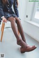 A woman sitting on a chair wearing black stockings.