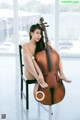 A woman sitting on a chair holding a cello.