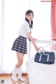 A young woman in a school uniform holding a bag.