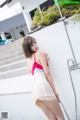 A woman in a white and red dress standing next to a pool.