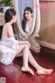 A woman sitting on the floor in front of a mirror.