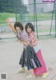 Two young women standing next to each other holding a baseball bat.