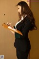 A woman in a business suit writing on a clipboard.