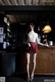 A woman standing in front of a bar wearing a skirt.