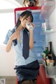 A woman in a blue shirt and tie drinking from a can.