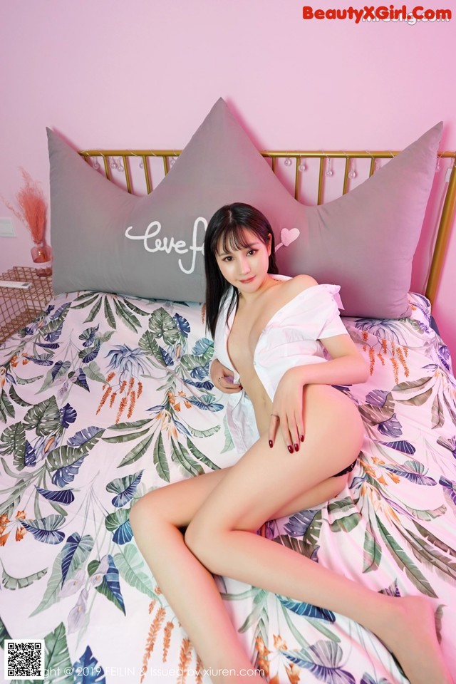 A woman sitting on top of a bed next to a pillow.