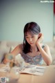 A woman sitting at a table with a book in front of her.