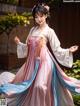 A woman in a pink and blue hanbok is posing for a picture.