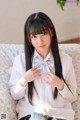 A young woman sitting on a couch with a bow tie.